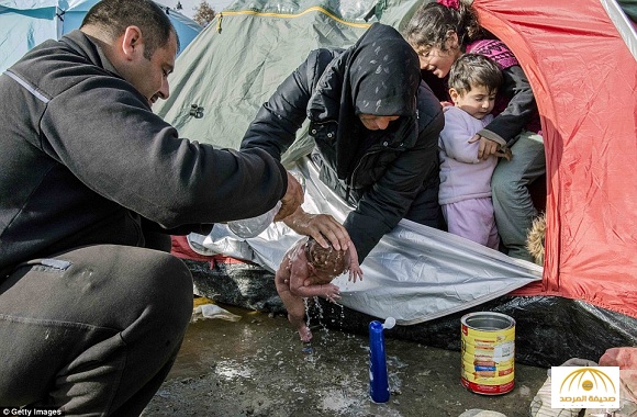 بالصور و الفيديو: عائلة سورية تضطر لغسل طفلها حديث الولادة بالخلاء على الحدود اليونانية