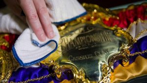 An exhibition assistant poses for a photograph whilst cleaning a replica 1964 Cassius Clay Championship Belt, during a photocall to preview the Muhammad Ali exhibition entitled "I Am The Greatest", at the O2 Arena in London on March 3, 2016. The exhibition at London's 02 Arena traces the story of the boxer from his childhood, through his glittering and brutal career to his elevation as a cultural and political icon. / AFP / JUSTIN TALLIS (Photo credit should read JUSTIN TALLIS/AFP/Getty Images)