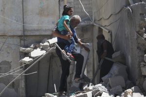 A man carries a girl as he makes his way through the rubble at a site hit by airstrike in the rebel-controlled area of Maaret al-Numan town in Idlib province, Syria, June 12, 2016. REUTERS/Khalil Ashawi