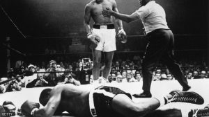 25 MAY 1965: CASSIUS CLAY OF THE UNITED STATES STANDS OVER THE PRONE FIGURE OF HEAVYWEIGHT CHAMPION SONNY LISTON DURING THEIR BOUT HELD IN LEWISTON, MAINE. CLAY WON THE FIGHT WITH A FIRST ROUND KNOCK-OUT TO CLAIM THE TITLE. Mandatory Credit: Allsport Hulton/Archive