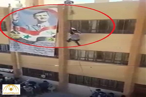 بالفيديو : لحظة سقوط طالب سوري موالي للنظام ميتاً أثناء رفع العلم فوق صورة بشار