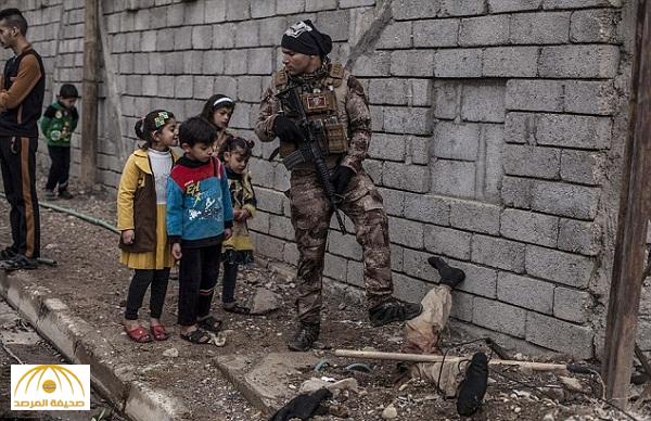 شاهد : صورة أطفال يقفون أمام مقاتل “داعشي” مدفون بالأرض و قدميه في الهواء