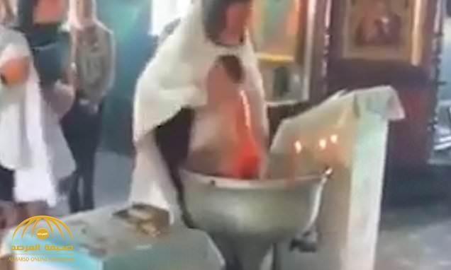 شاهد : كاهن روسي داخل كنيسة يضع  طفل تحت الماء بطريقة عنيفة .. والأم تتدخل لإنقاذه!