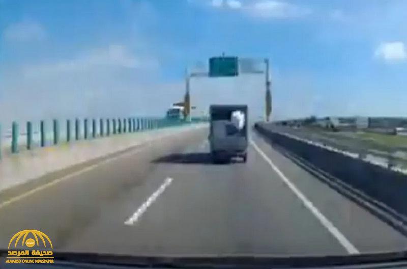 شاهد .. فيديو محير لصندوق يسقط مرتين من شاحنة على طريق سريع ويعود إليها !