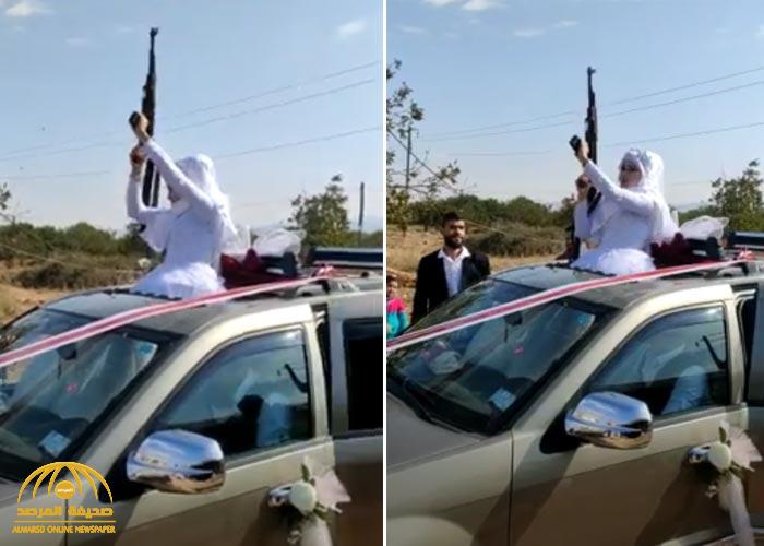شاهد.. عروس عربية "محجبة" تخرج من سقف سيارة الزفاف وتطلق الرصاص من سلاح رشاش!