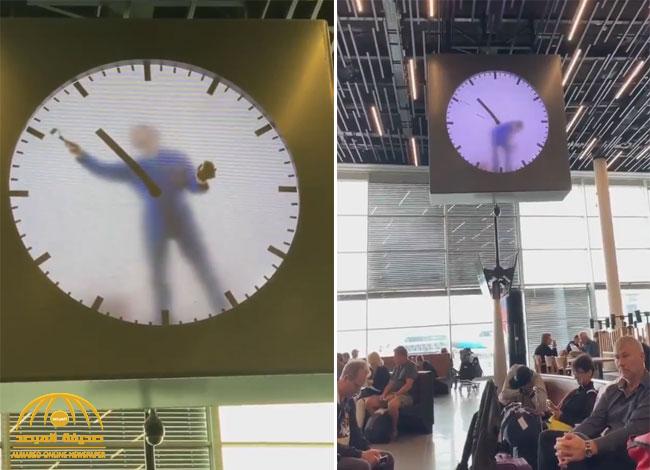 شاهد.. ساعة أغرب من الخيال بداخلها شخص يرسم عقاربها كل دقيقة في مطار بهولندا