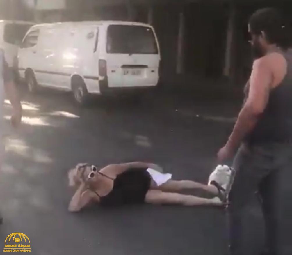 شاهد.. امرأة لبنانية تفترش الطريق بجسدها وتمنع مرور السيارات: "أنا هون بدي أقطع"