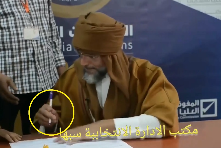 ‏لأول مرة.. شاهد: مكان إصابة ⁧‫سيف الإسلام القذافي‬⁩ بوضوح في يده أثناء توقيعه على أوراق ترشحه لـ ⁧‫الانتخابات الليبية